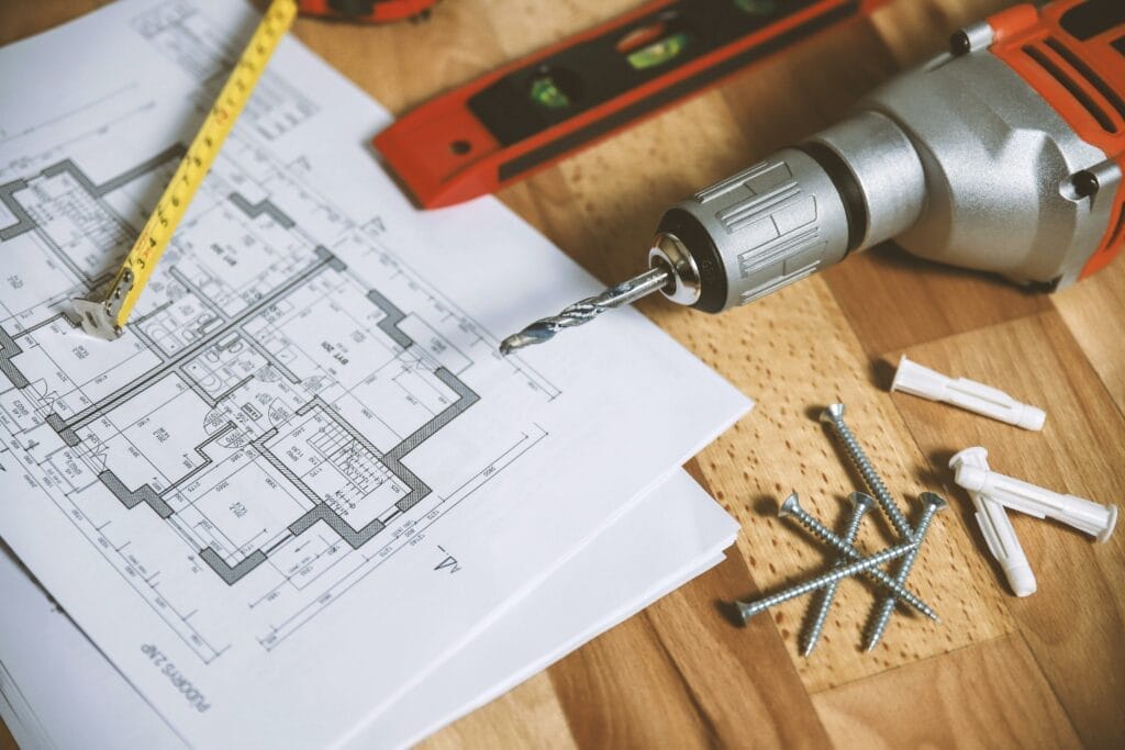 Blueprint on desk with drill, nails and ruler